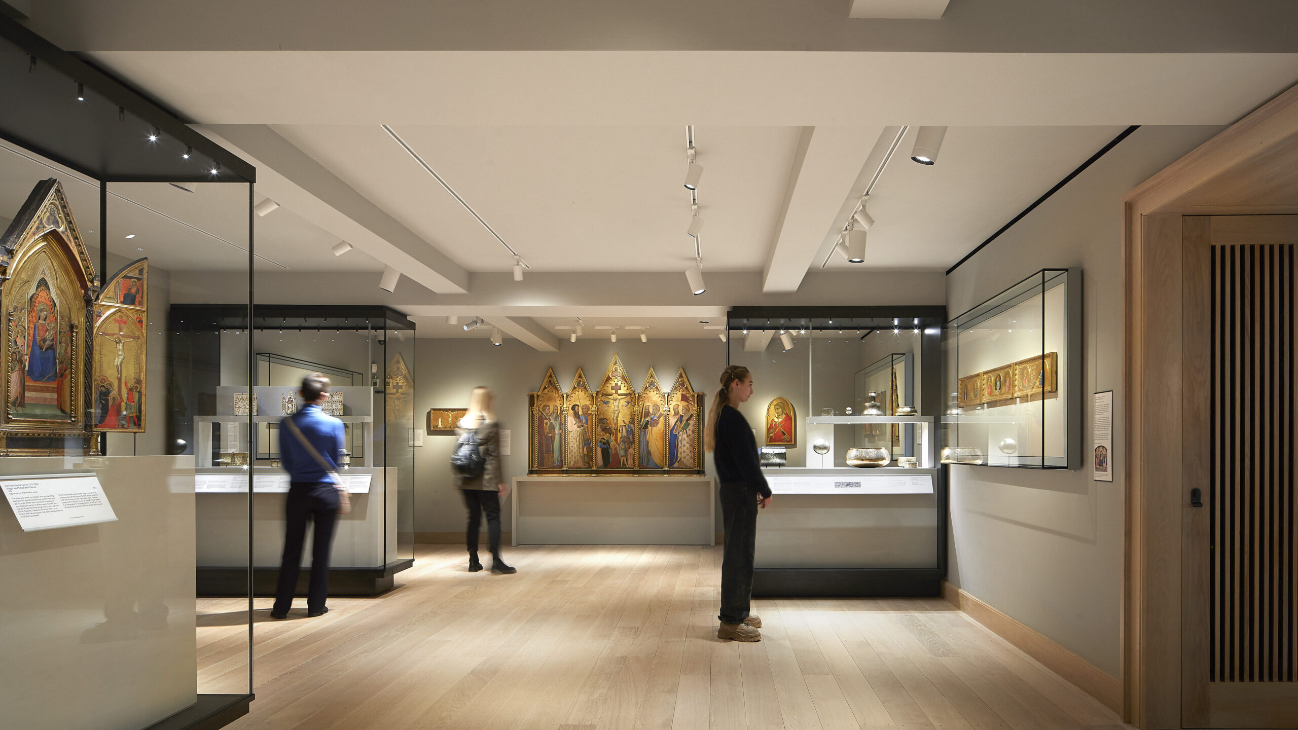 Three people standing in a gallery looking at objects from the Medieval and Early Renaissance period
