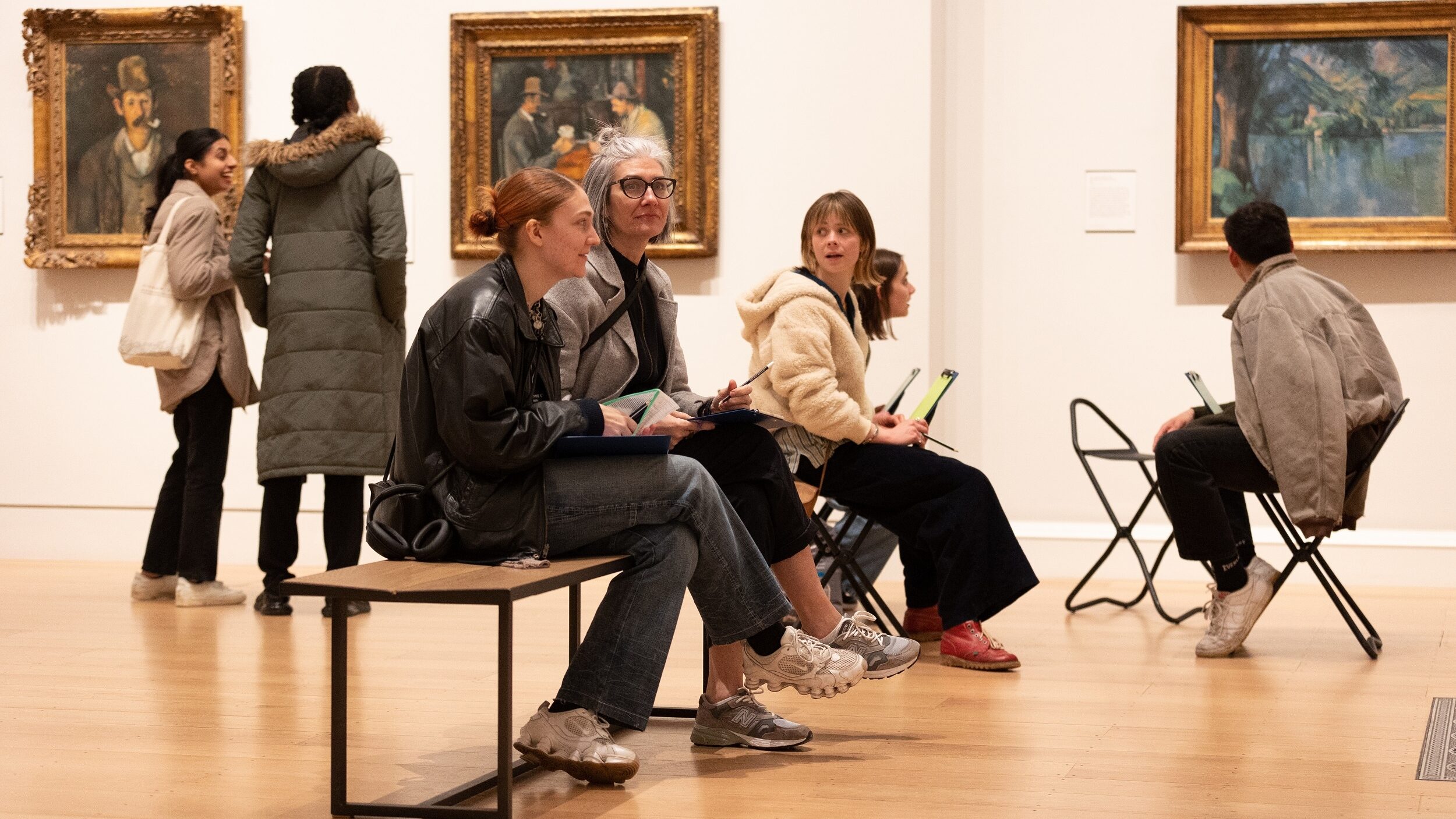 A group of people sit on a bench inside The Courtauld Gallery