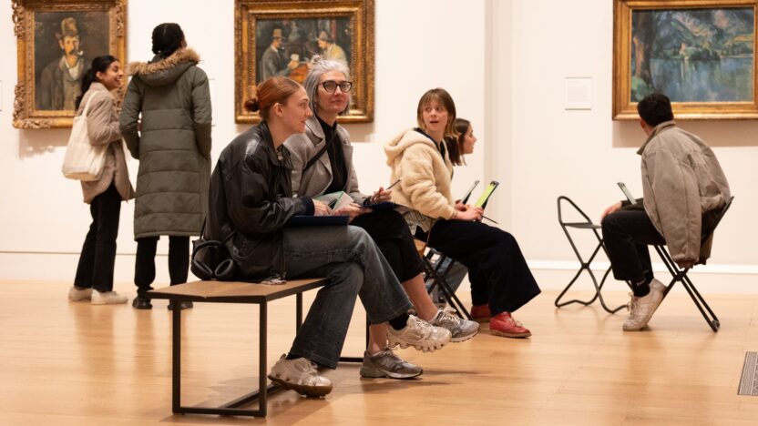 A group of people sit on a bench inside The Courtauld Gallery