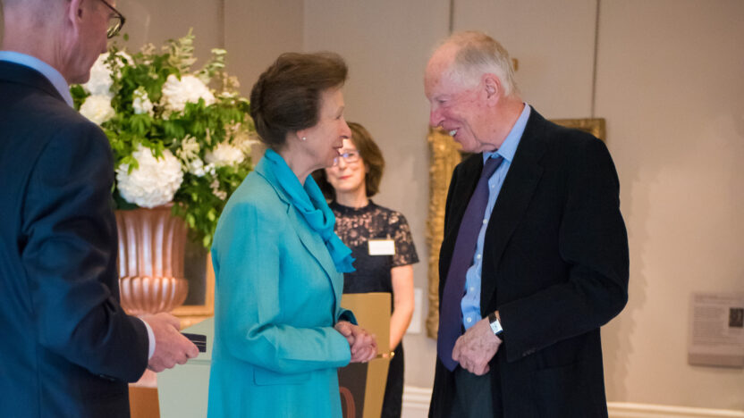 Lord Rothschild and Princess Anne smiling and talking together, with Deborah Swallow visible in the background, at The Courtauld Gallery in 2018.