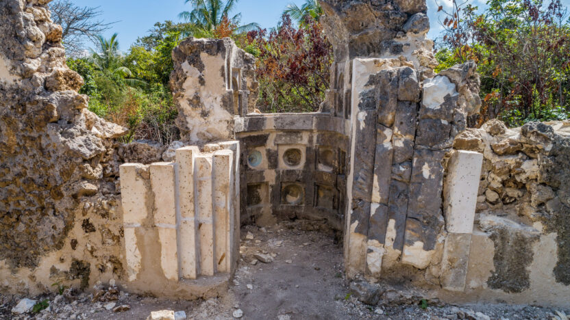 Photograph of a stone structure surrounded by bushes and trees