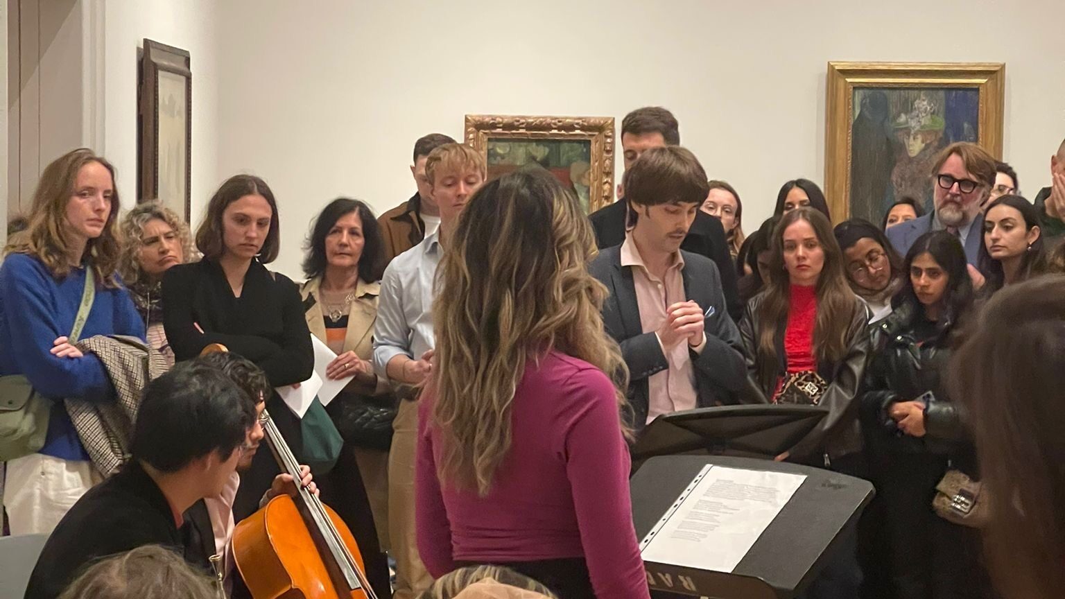 A large crowd surrounds a musical performance in an art gallery