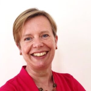 a woman with short blond hair and a red shirt smailing at the camera