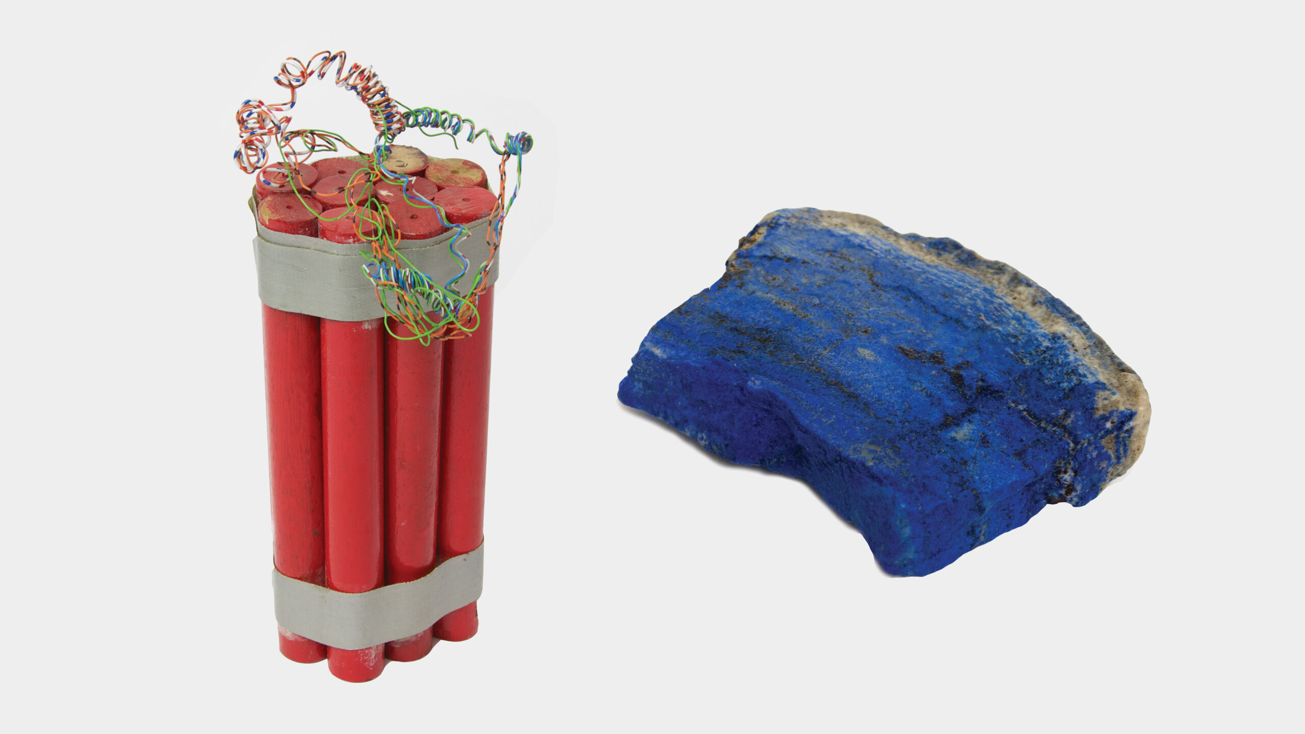 Two merged photographs showing their corresponding artists things. To the left, a red prop dynamite belonging to Cornelia Parker, made in wood, showing six sticks of dynamite taped together. To the right a chunk of Lapis belonging to the artist Christopher Le Brun.