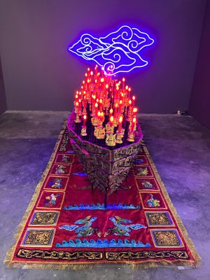 FX Harsono (Indonisia), Traces of Historical Journeys, 2023. Installation with embroidery on textile, old wood carving, electric candle, LED neon flex, acrylic, iron, 140 x 250 x 150 cm. Courtesy of the artist.