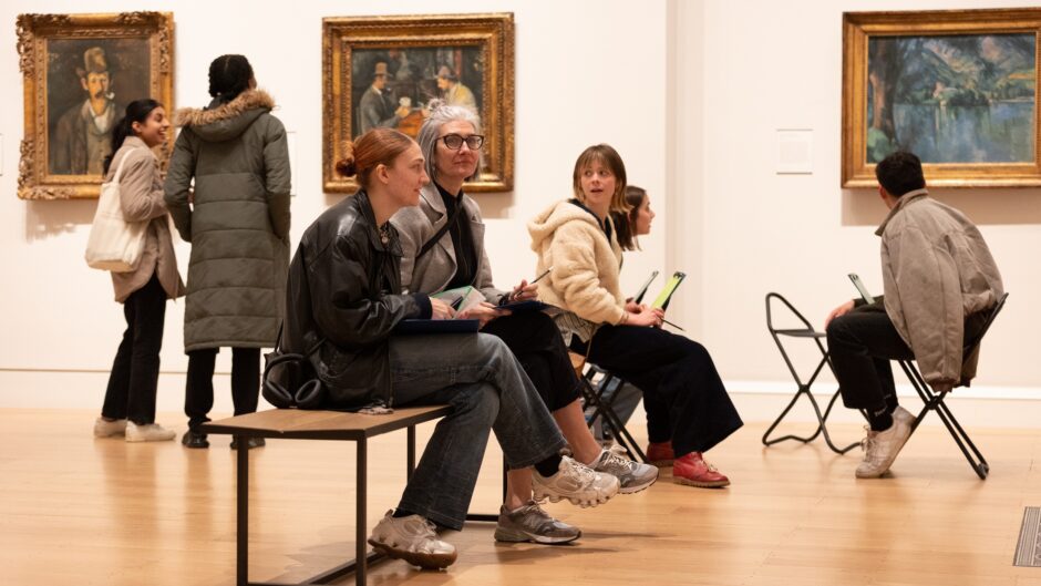 A group of people sit on a bench inside The Courtauld Gallery