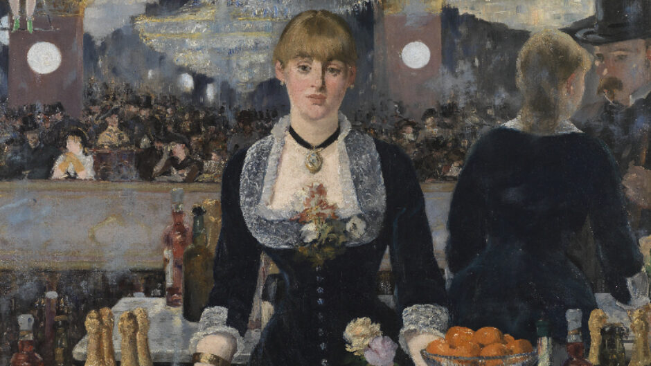 A woman standing behind a bar facing straight ahead.