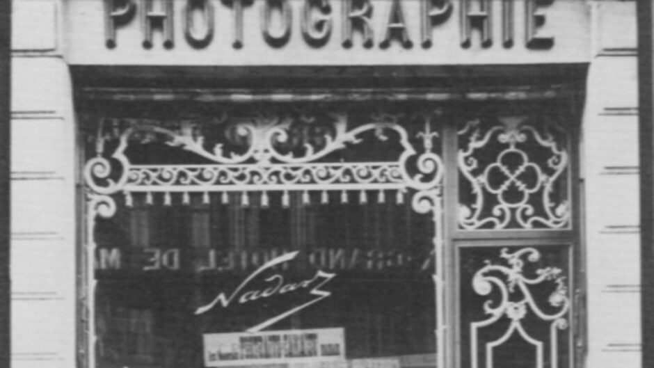A black and white photograph of several people looking into a photography studio.