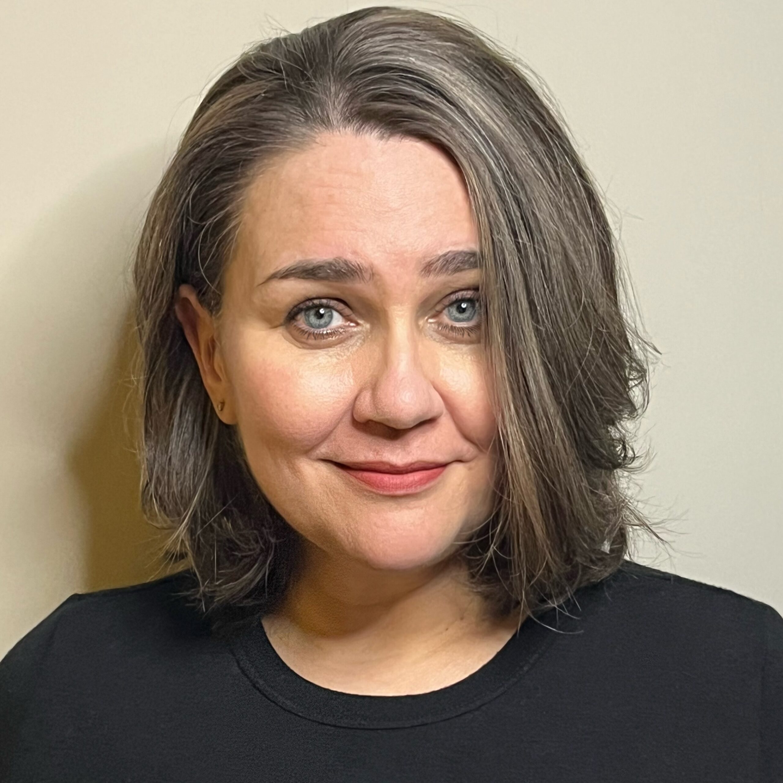 Photo of a woman with brown hair and light eyes, smiling