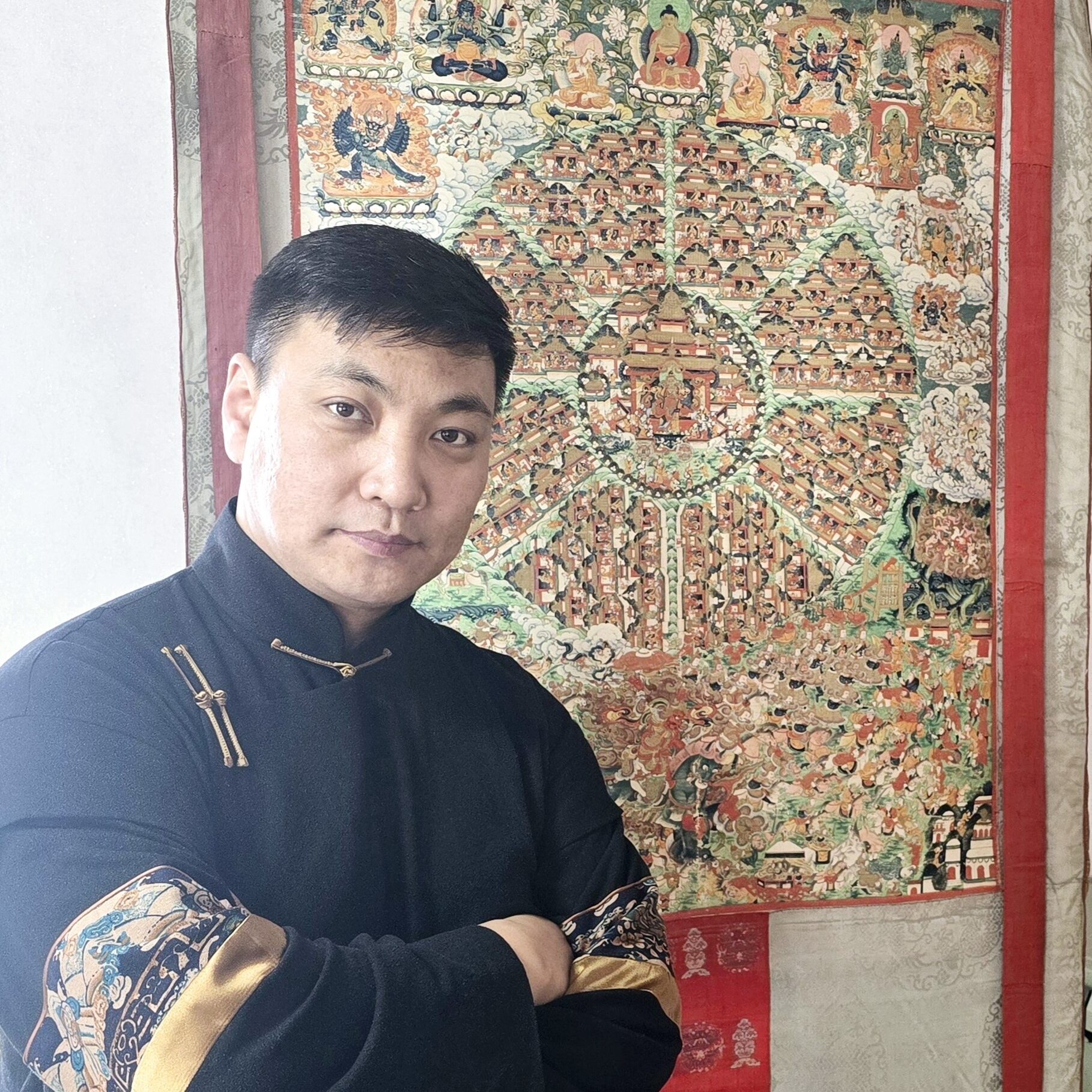 a man with short hair in traditional dress in front of a decorative fabric panel