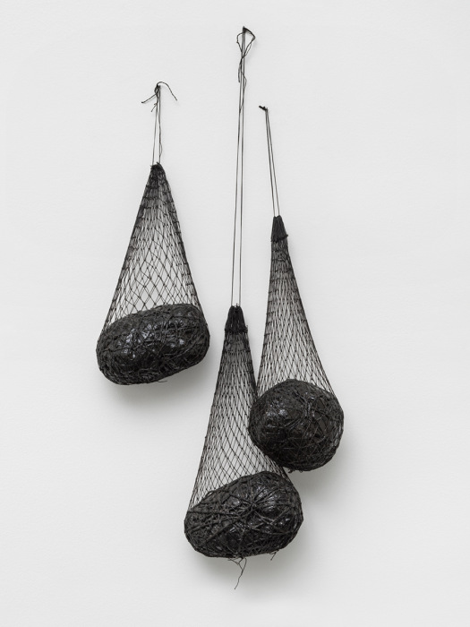 three black net sculptures pinned to a white wall