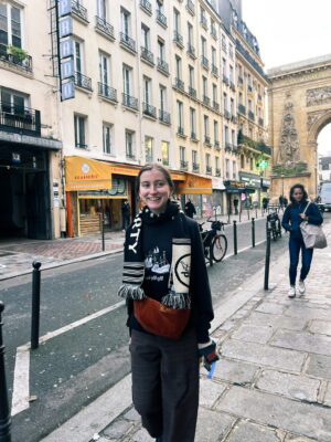Ellen standing on a street in Paris, smiling.
