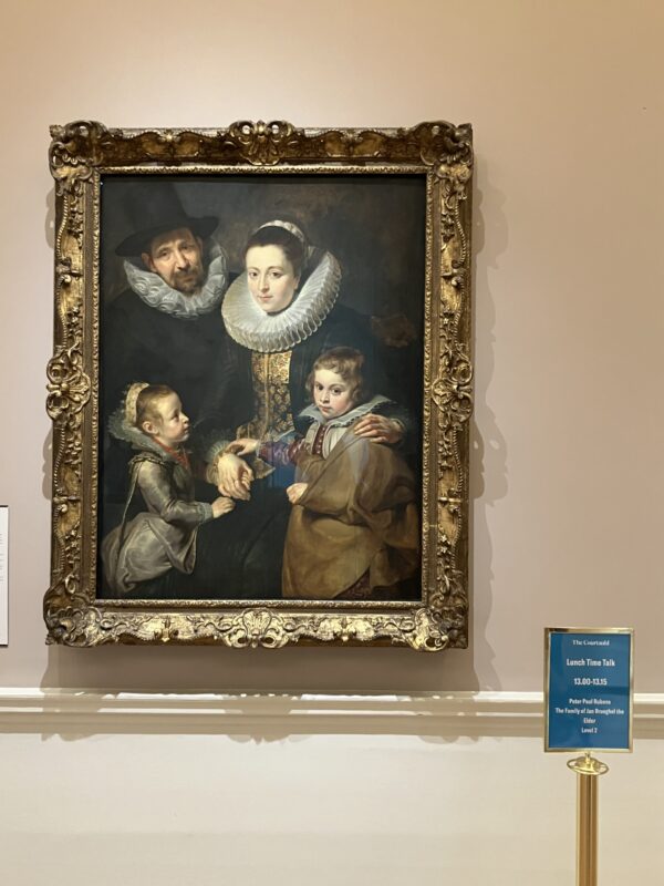 A painting of a family by Gainsborough, on display at The Courtauld Gallery, with a sign for a student talk here at 4pm in front of it.