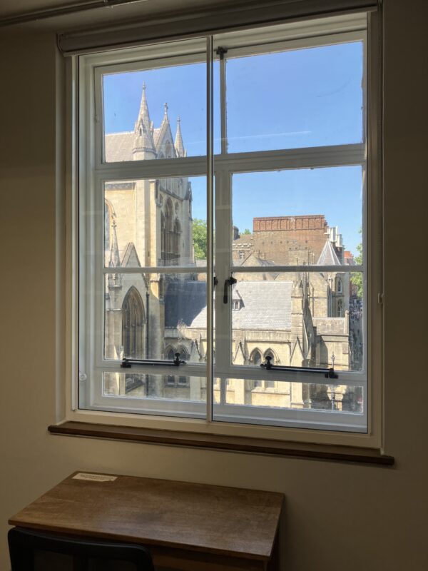 A library desk situated in front of a large window in London, looking out onto a sunny day.