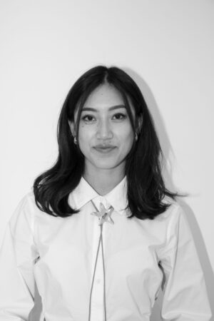 Black and white photograph of Raina Chan, wearing a white shirt and with dark shoulder length hair.