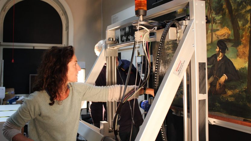 Woman using technical equipment to examine a painting