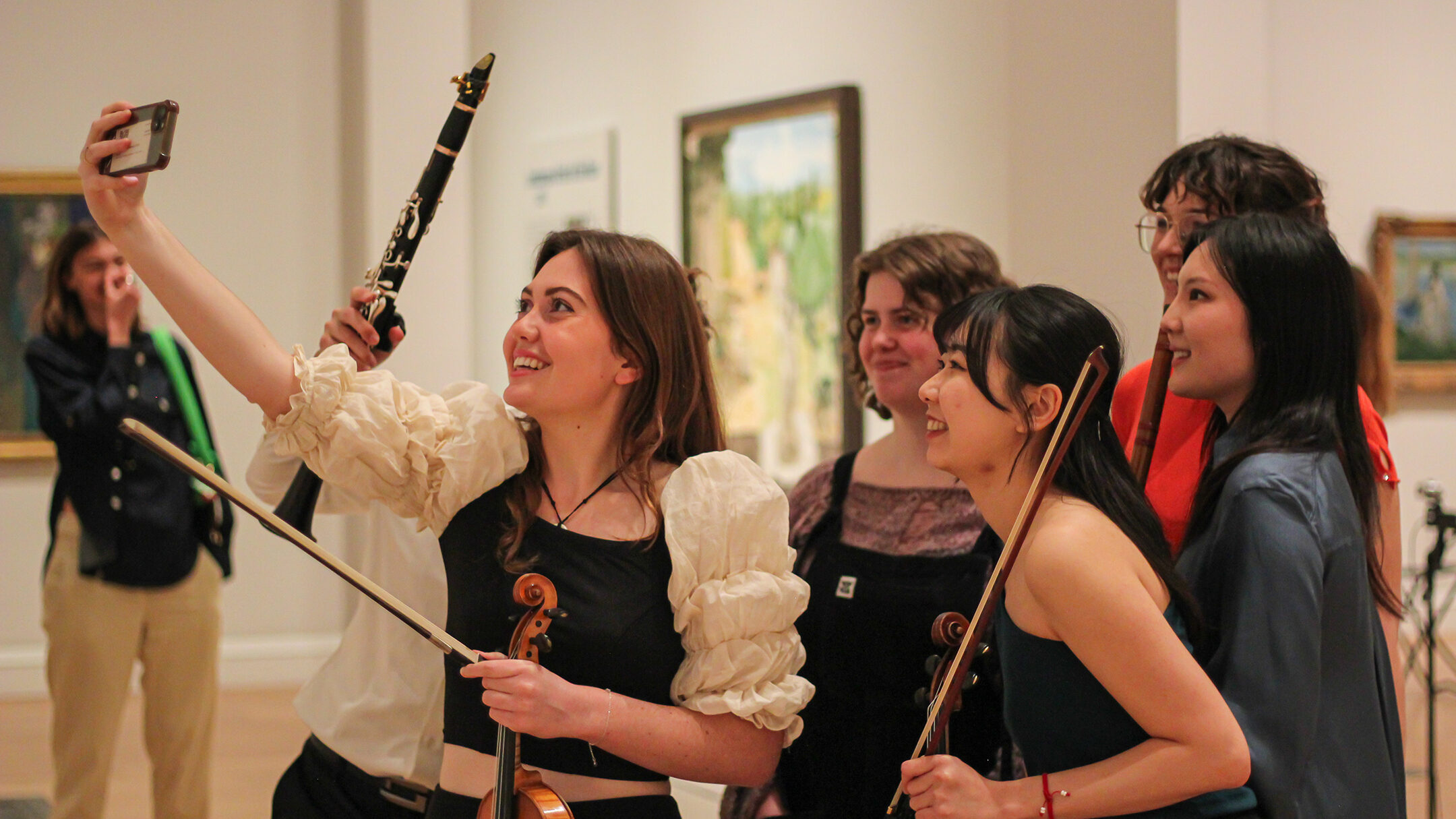A group of musicians take a selfie whilst holding their instruments in the courtauld gallery.