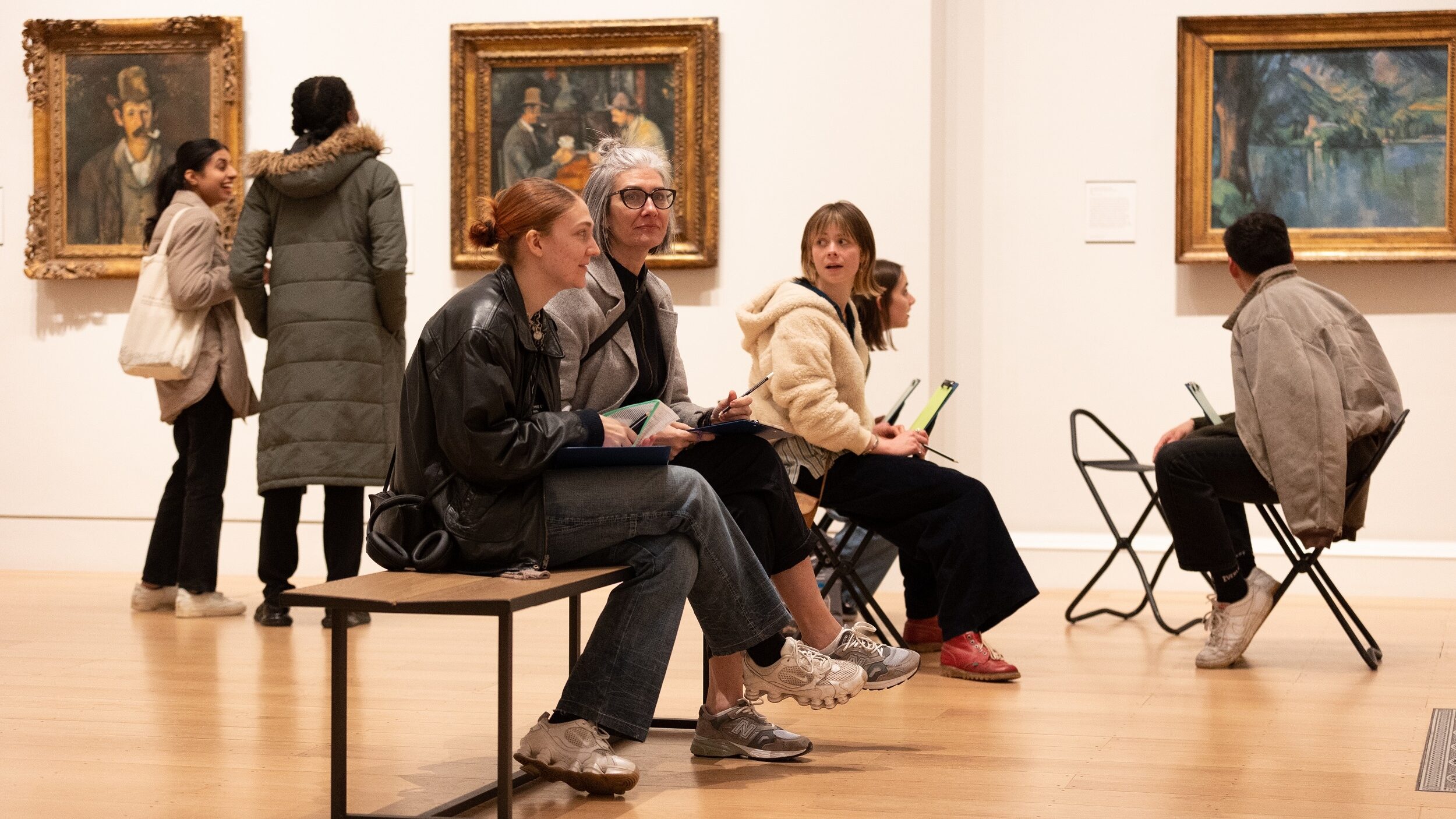 A group of people sit on a bench inside The Courtauld Gallery