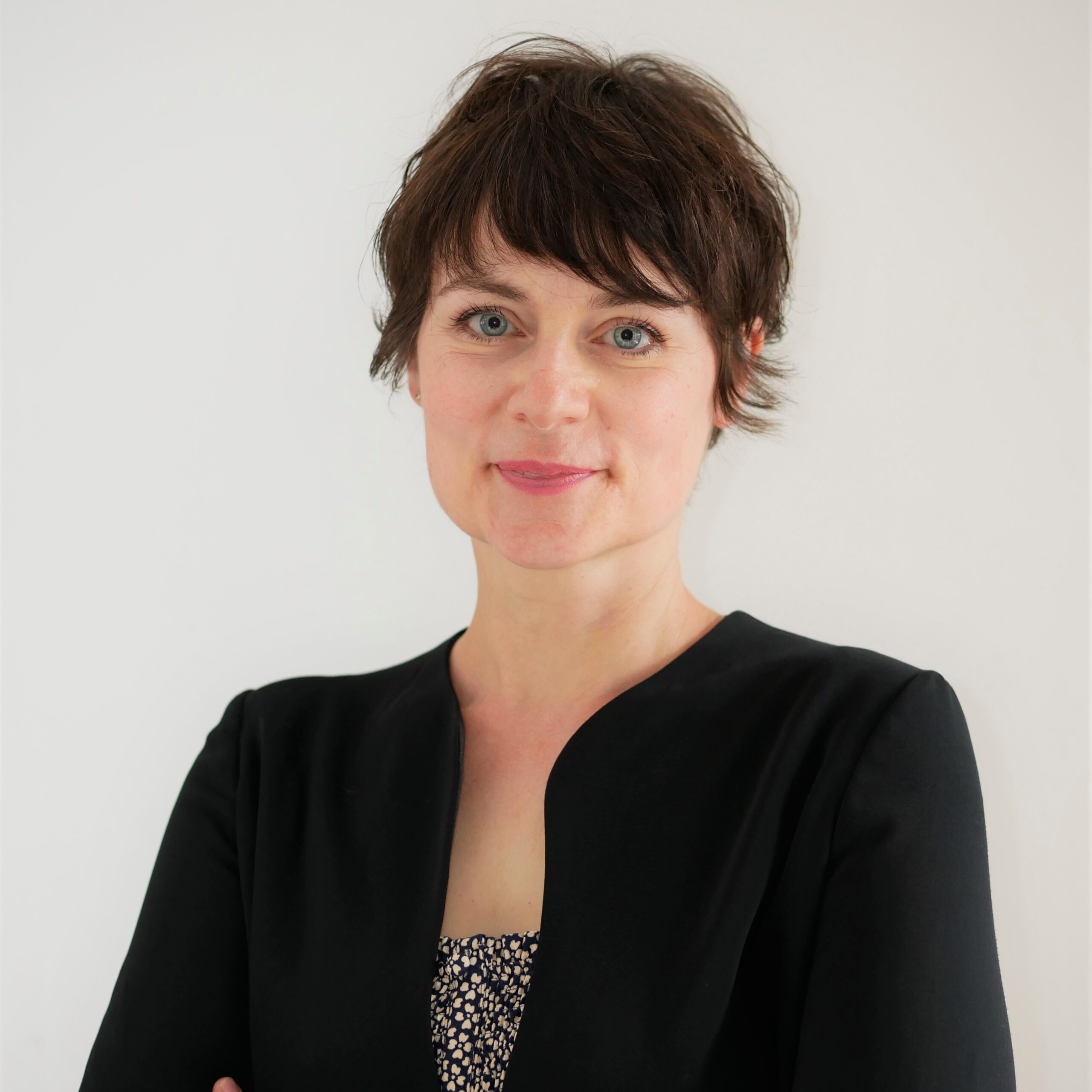 Headshot of woman with arms folded, wearing black jacket.