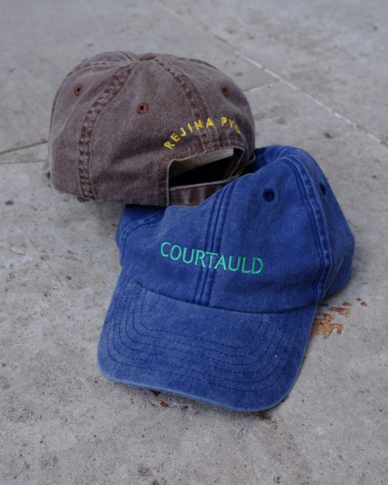 Photograph of two caps, one blue and one brown, with Courtauld and Rejina Pyo branding embroidered on front and back.