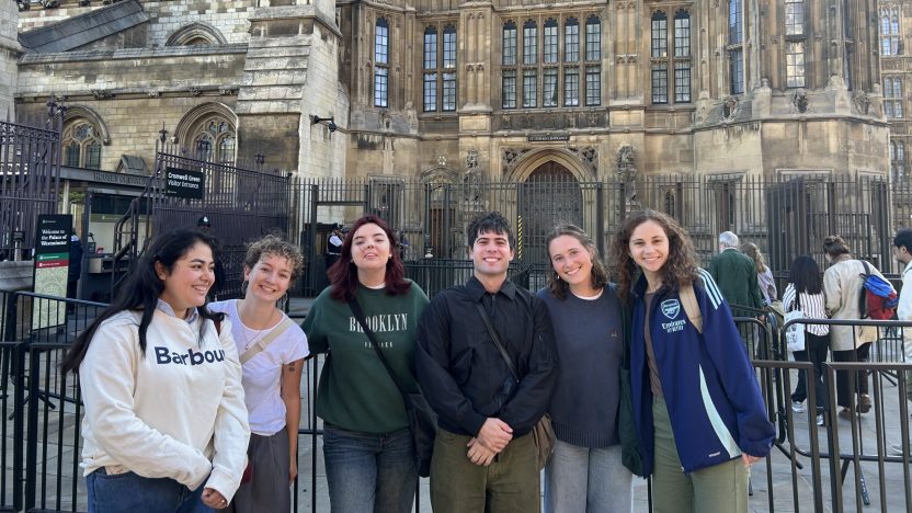 A group of six students stand together outside Parliament