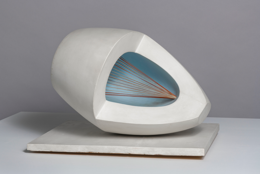 a wooden abstract sculpture featuring an oval form with pale blue and red painted surfaces, intersected by strings and mounted on a painted wooden base.