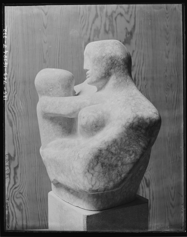 Black and white photo of a white alabaster sculpture of a woman holding a child, on a plinth, against a neutral background.