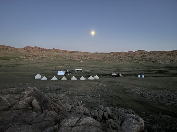 A row of tents in a Mongolian landscape with the moon above.