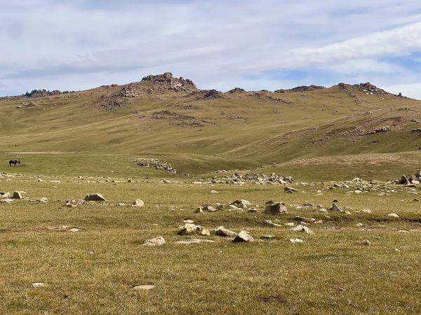 Green, rocky mountainous landscape, blue sky.
