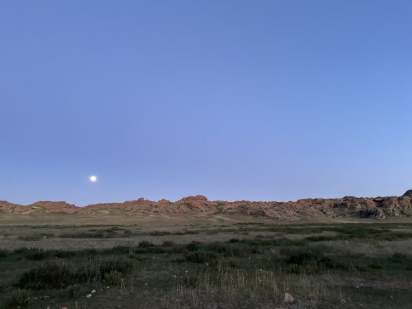 evening view over a Mongolian landscape with a partial moon.