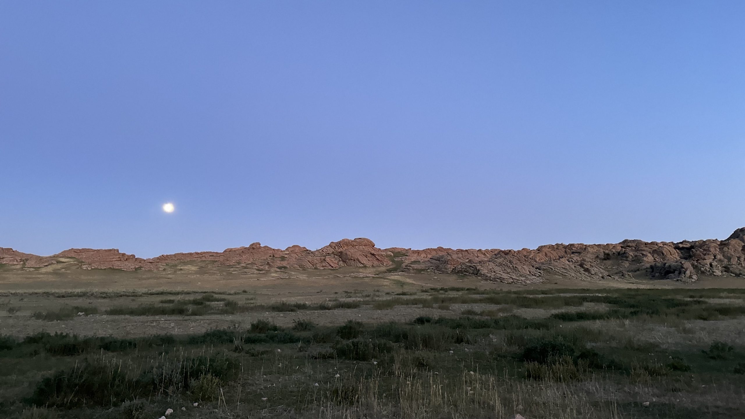 evening view over a Mongolian landscape with a partial moon.