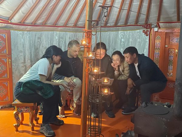 a group sits around discussing inside a tradtional Mongolian tent.