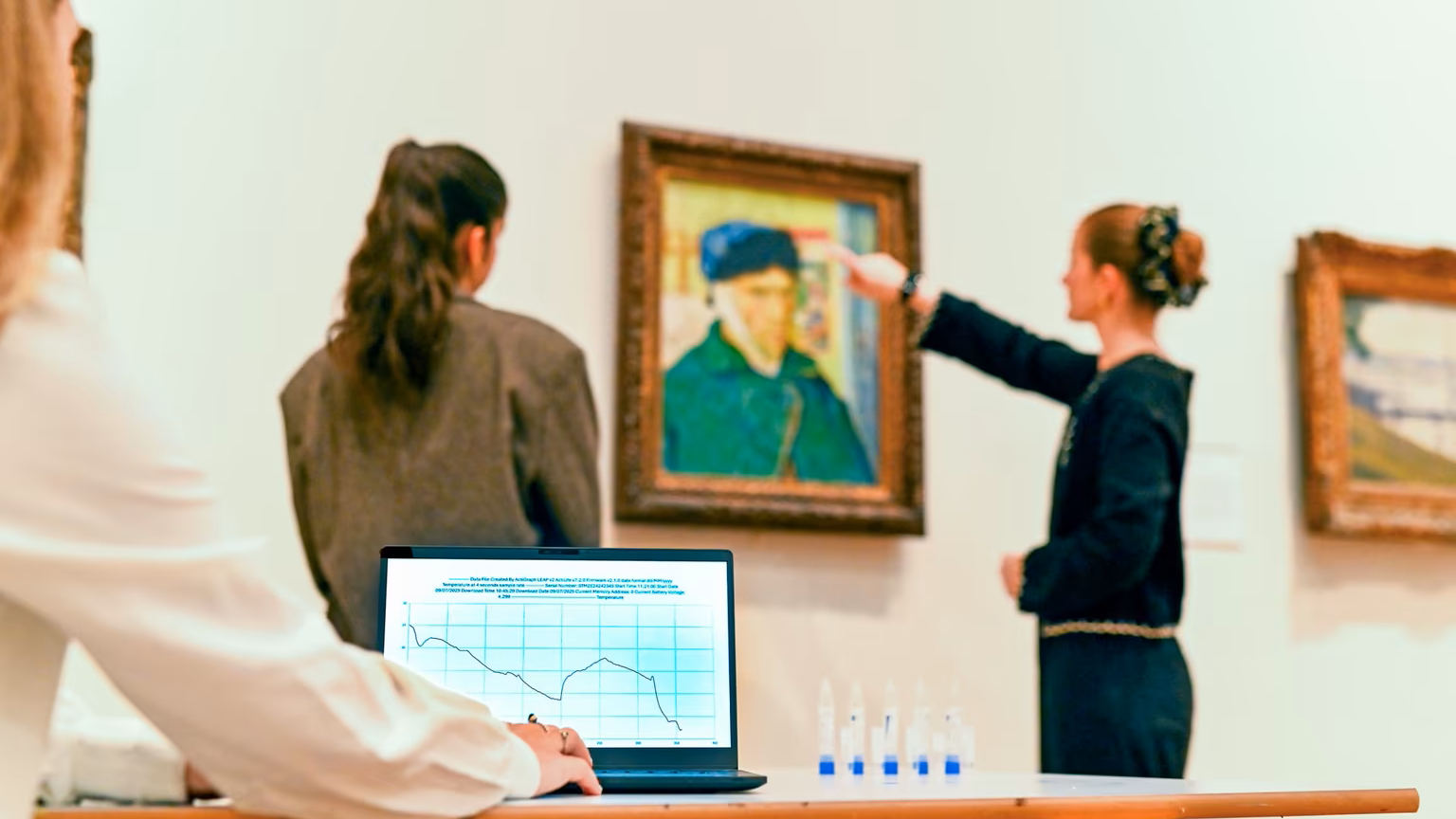 Two visitors look at Van Gogh's Self Portrait with Bandaged Ear whilst someone records their reaction on a laptop