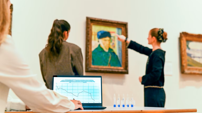 Two visitors look at Van Gogh's Self Portrait with Bandaged Ear whilst someone records their reaction on a laptop