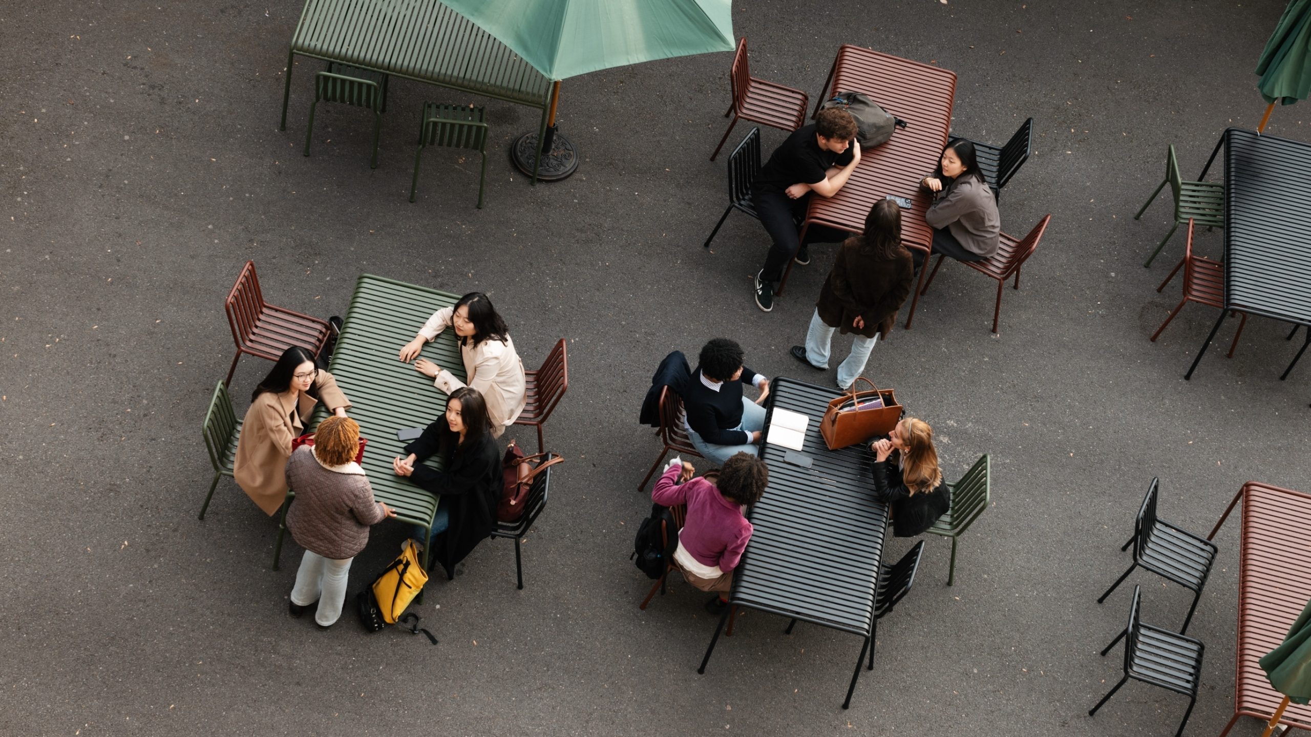 A view from above of a series of outdoor tables where students are sitting and talking to each other