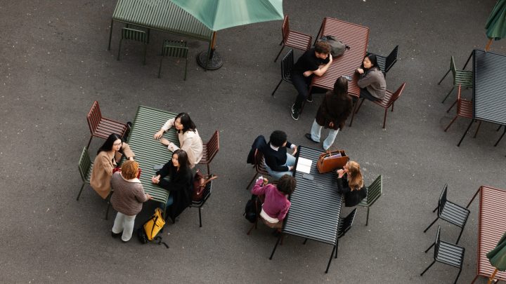 A view from above of a series of outdoor tables where students are sitting and talking to each other