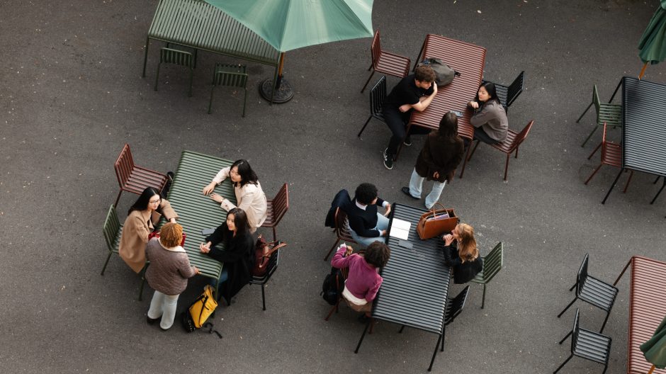 A view from above of a series of outdoor tables where students are sitting and talking to each other