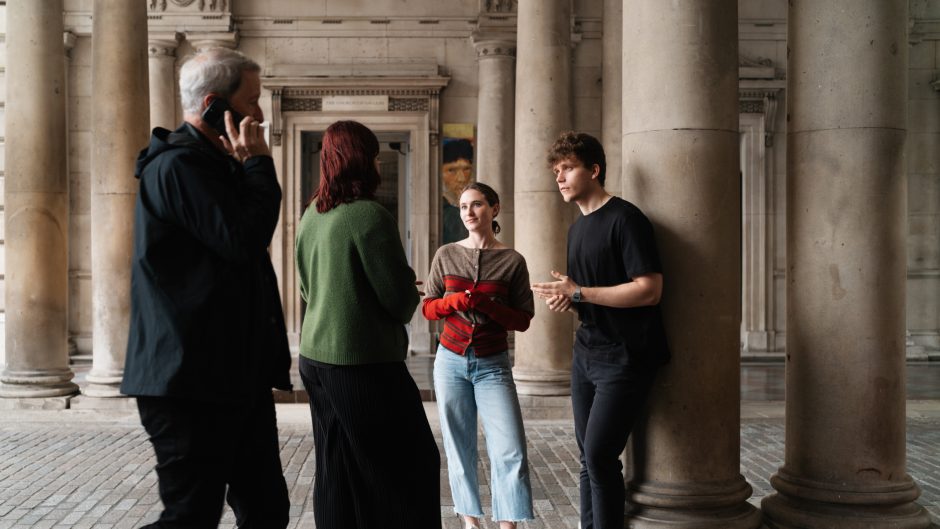 Three students talk outside Somerset House, while a man on the phone walks past.
