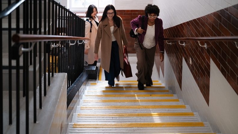 Three students walk up stairs at Vernon Square campus.