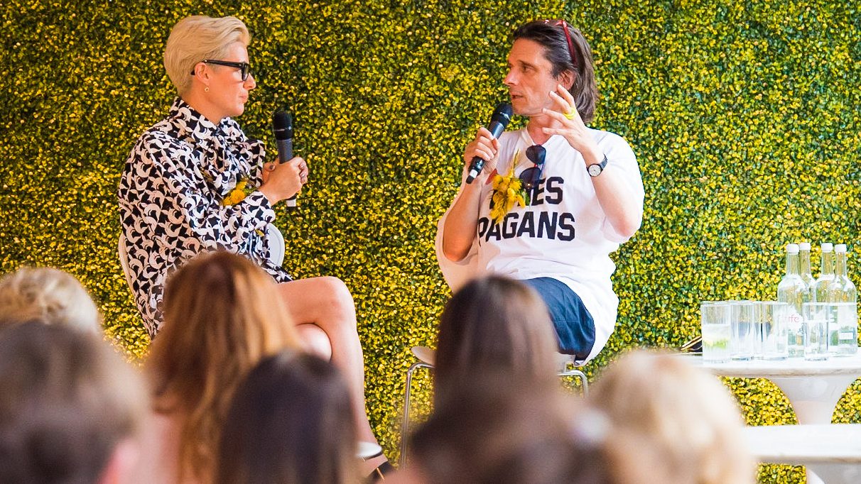two people on a stage one is interviewing the other, there is a crowd sitting and listening to them