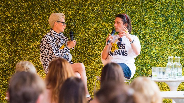 two people on a stage one is interviewing the other, there is a crowd sitting and listening to them