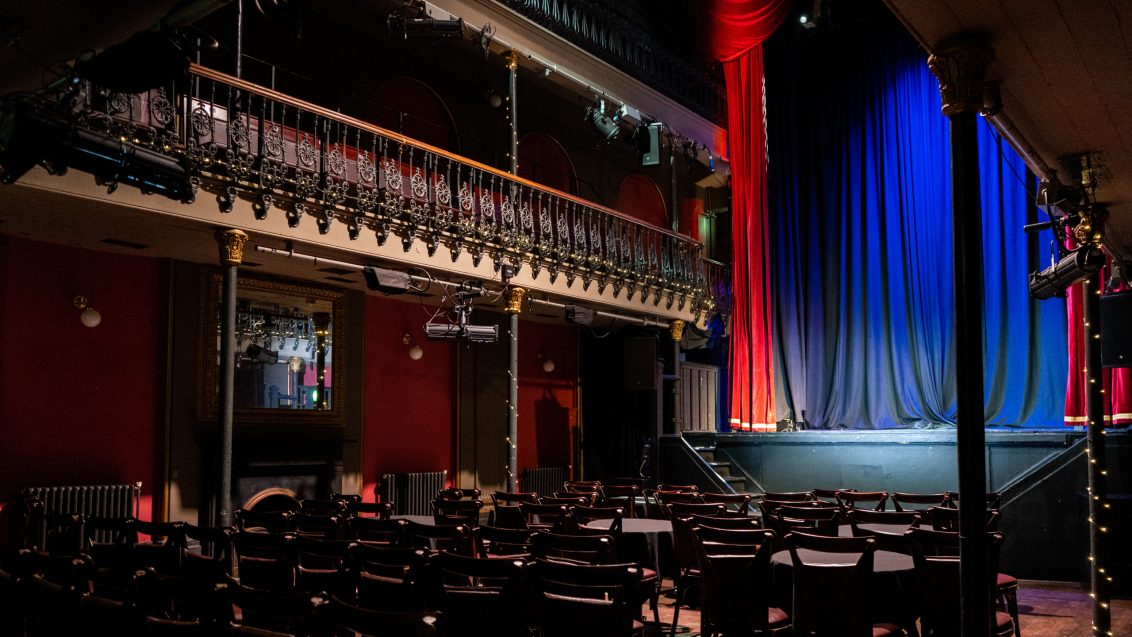 A theatre with chairs and red and blue curtains
