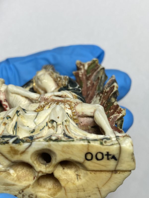 the base of a glazed sculture depicting Jesus praying in the garden of Gethsemane. seated sleeping disciples sit beneath him.