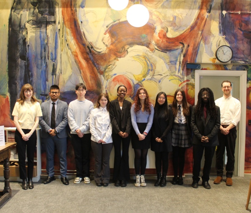A group of students post for photo in front of a colourful wall