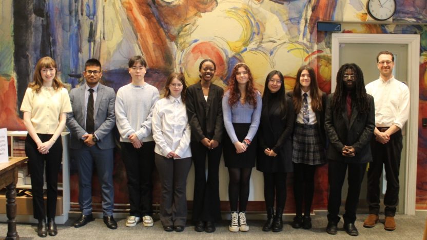 A group of students post for photo in front of a colourful wall