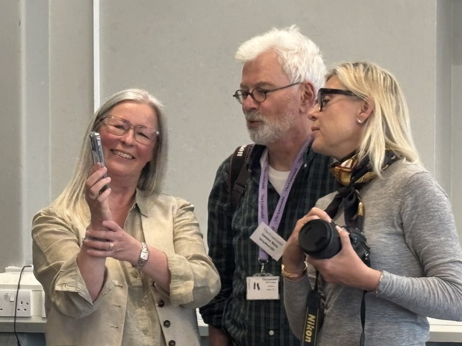 Photograph of three students gathered around each other with a camera