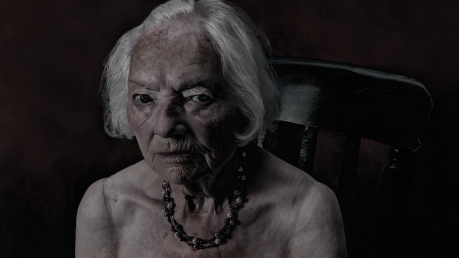 Contemporary portrait photograph of a woman from Glasgow, shown from the shoulders up against a neutral background, with direct gaze and natural lighting emphasizing facial features and expression, part of a series exploring identity and perception.