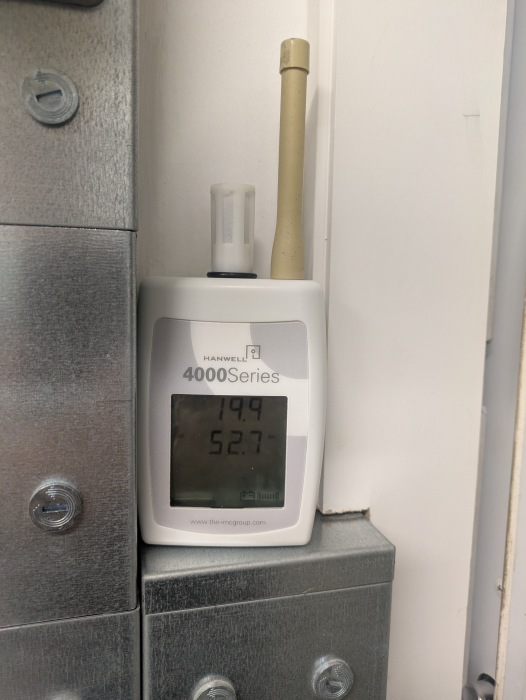 An environmental monitor sits on a ledge in a room taking a reading.