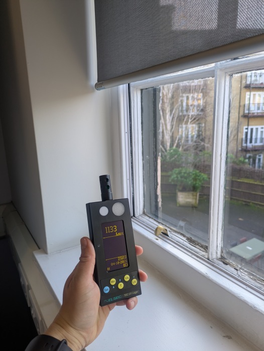Light monitor held up to a window, taking a reading of 1133 lux