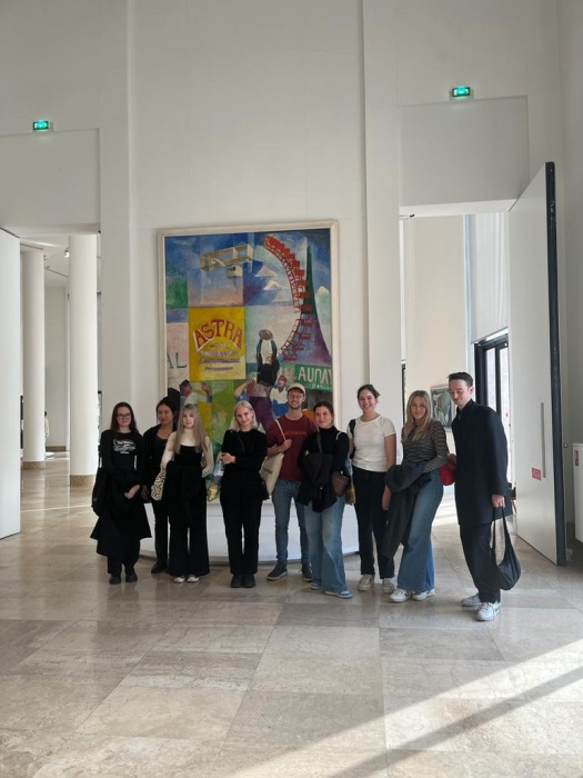 Group of students post for a photo in a gallery